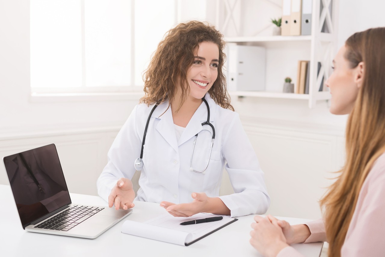 Provider sitting at a desk with a patient showing a laptop screen to her