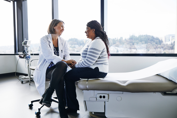 Provider and patient sitting in a room. The patient is holding the providers' hands