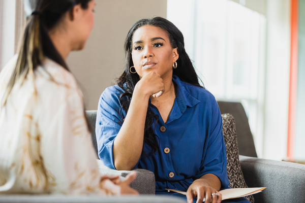  An empathetic mid adult female counselor sits with her hand on her chin as she listens to the unrecognizable mid adult female client.