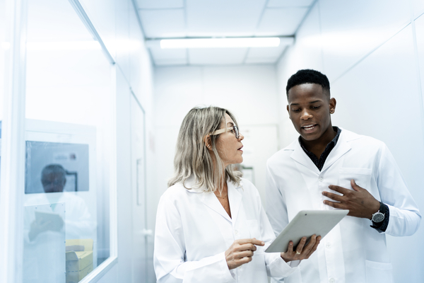 Two scientists discussing a finding that is on a tablet